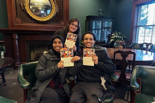 Three students from the educators of color network hold a book